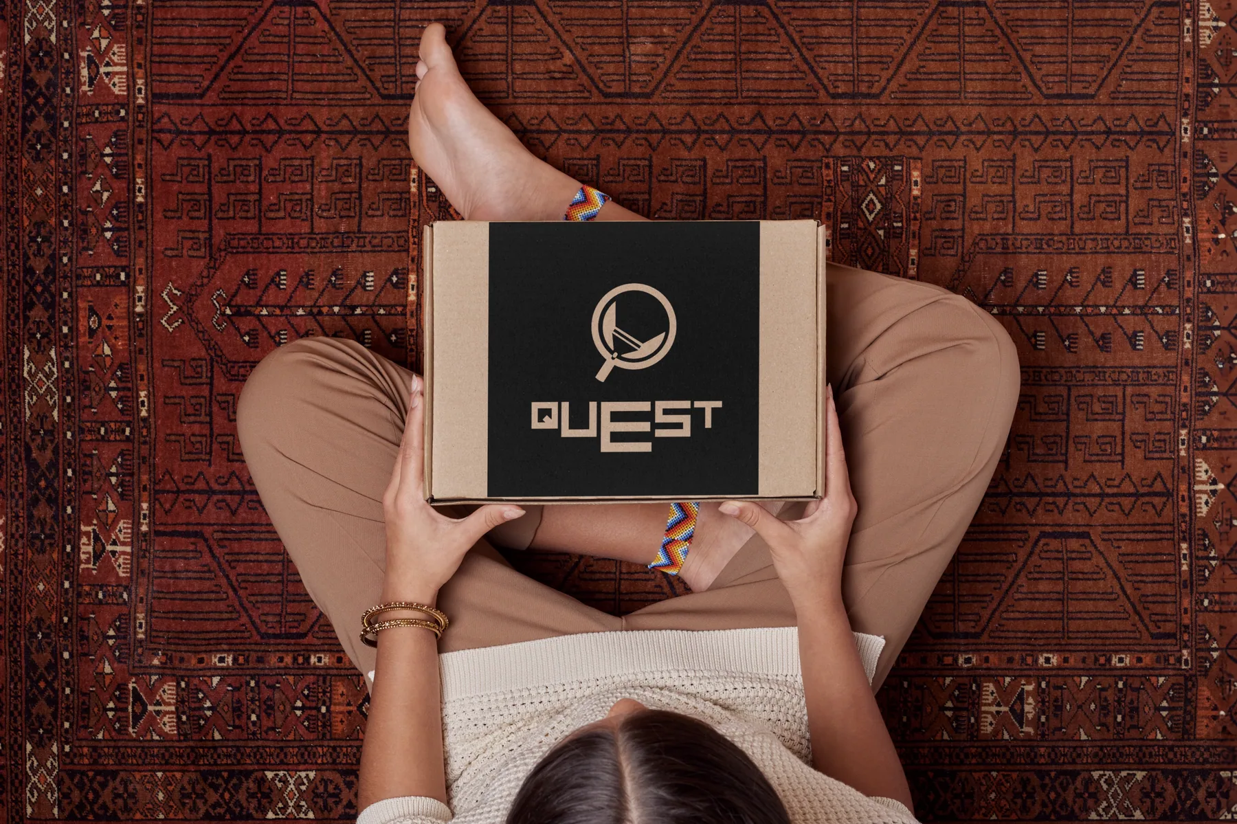 Quest branded box held on a patterned rug